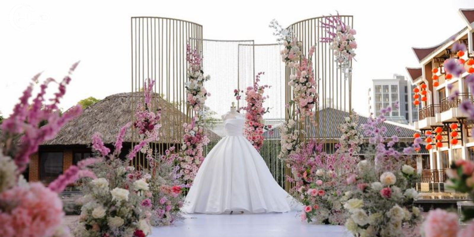 Backdrop Đám Cưới Ngoài Trời Phong Cách Châu Âu Đẹp Xuất Sắc  Một đám cưới ngoài trời luôn mang đến cảm giác lãng mạn, tự do và đầy cảm xúc. Khi không gian thiên nhiên được kết hợp cùng nghệ thuật trang trí tinh tế, buổi lễ cưới trở thành một khung cảnh như bước ra từ câu chuyện cổ tích. Trong đó, backdrop đám cưới ngoài trời chính là chi tiết quan trọng tạo nên linh hồn của toàn bộ không gian lễ cưới.  Nếu sân khấu là nơi cô dâu chú rể thực hiện những nghi thức thiêng liêng, thì backdrop đám cưới ngoài trời chính là phông nền giúp khoảnh khắc ấy trở nên hoàn hảo hơn. Một thiết kế đẹp không chỉ tạo điểm nhấn nổi bật cho buổi lễ mà còn giúp mọi bức ảnh cưới trở nên sang trọng và đầy cảm xúc.  Trong những năm gần đây, xu hướng backdrop đám cưới ngoài trời phong cách châu Âu đang được nhiều cặp đôi yêu thích. Phong cách này mang đến vẻ đẹp tinh tế, thanh lịch nhưng vẫn rất lãng mạn. Những chi tiết như hoa tươi, khung vòm, rèm lụa mềm mại hay ánh đèn vàng ấm áp giúp không gian lễ cưới trở nên nhẹ nhàng và đầy cảm
