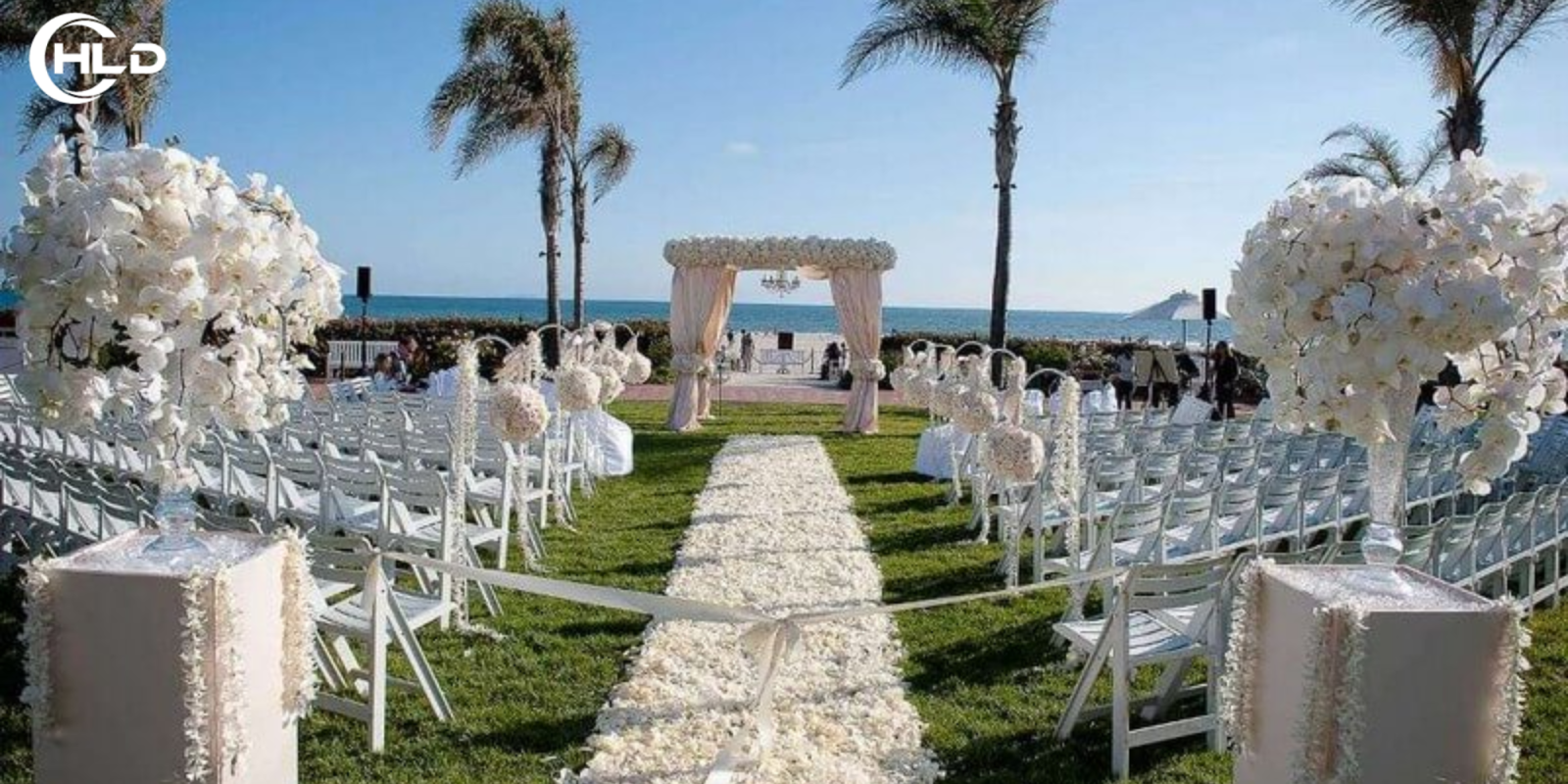 Backdrop Đám Cưới Ngoài Trời Phong Cách Châu Âu Đẹp Xuất Sắc  Một đám cưới ngoài trời luôn mang đến cảm giác lãng mạn, tự do và đầy cảm xúc. Khi không gian thiên nhiên được kết hợp cùng nghệ thuật trang trí tinh tế, buổi lễ cưới trở thành một khung cảnh như bước ra từ câu chuyện cổ tích. Trong đó, backdrop đám cưới ngoài trời chính là chi tiết quan trọng tạo nên linh hồn của toàn bộ không gian lễ cưới.  Nếu sân khấu là nơi cô dâu chú rể thực hiện những nghi thức thiêng liêng, thì backdrop đám cưới ngoài trời chính là phông nền giúp khoảnh khắc ấy trở nên hoàn hảo hơn. Một thiết kế đẹp không chỉ tạo điểm nhấn nổi bật cho buổi lễ mà còn giúp mọi bức ảnh cưới trở nên sang trọng và đầy cảm xúc.  Trong những năm gần đây, xu hướng backdrop đám cưới ngoài trời phong cách châu Âu đang được nhiều cặp đôi yêu thích. Phong cách này mang đến vẻ đẹp tinh tế, thanh lịch nhưng vẫn rất lãng mạn. Những chi tiết như hoa tươi, khung vòm, rèm lụa mềm mại hay ánh đèn vàng ấm áp giúp không gian lễ cưới trở nên nhẹ nhàng và đầy cảm
